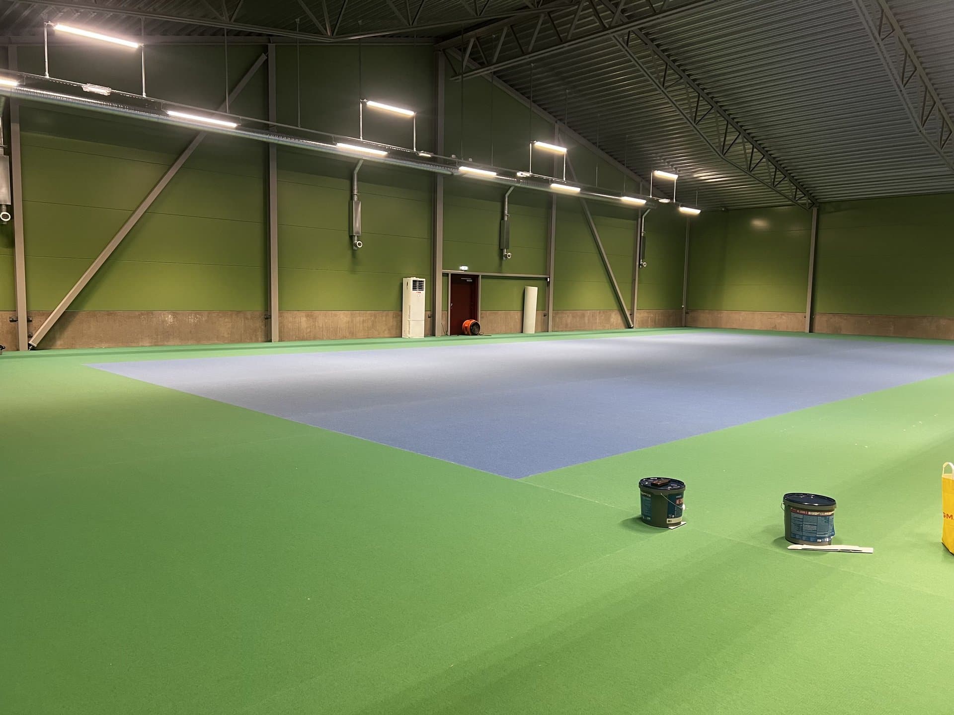 Färdig sportgolv-hall installerad av Svensk Filterservice — ljusblå spelplan på grön bakgrund
